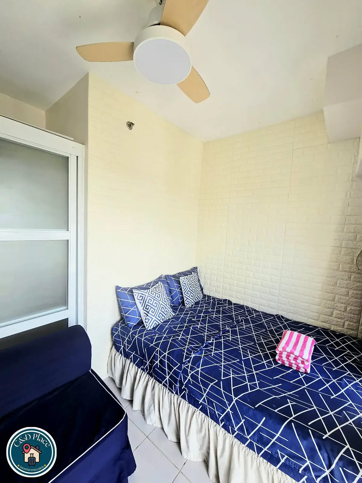 Double bed with navy bedding beside a single sofa bed