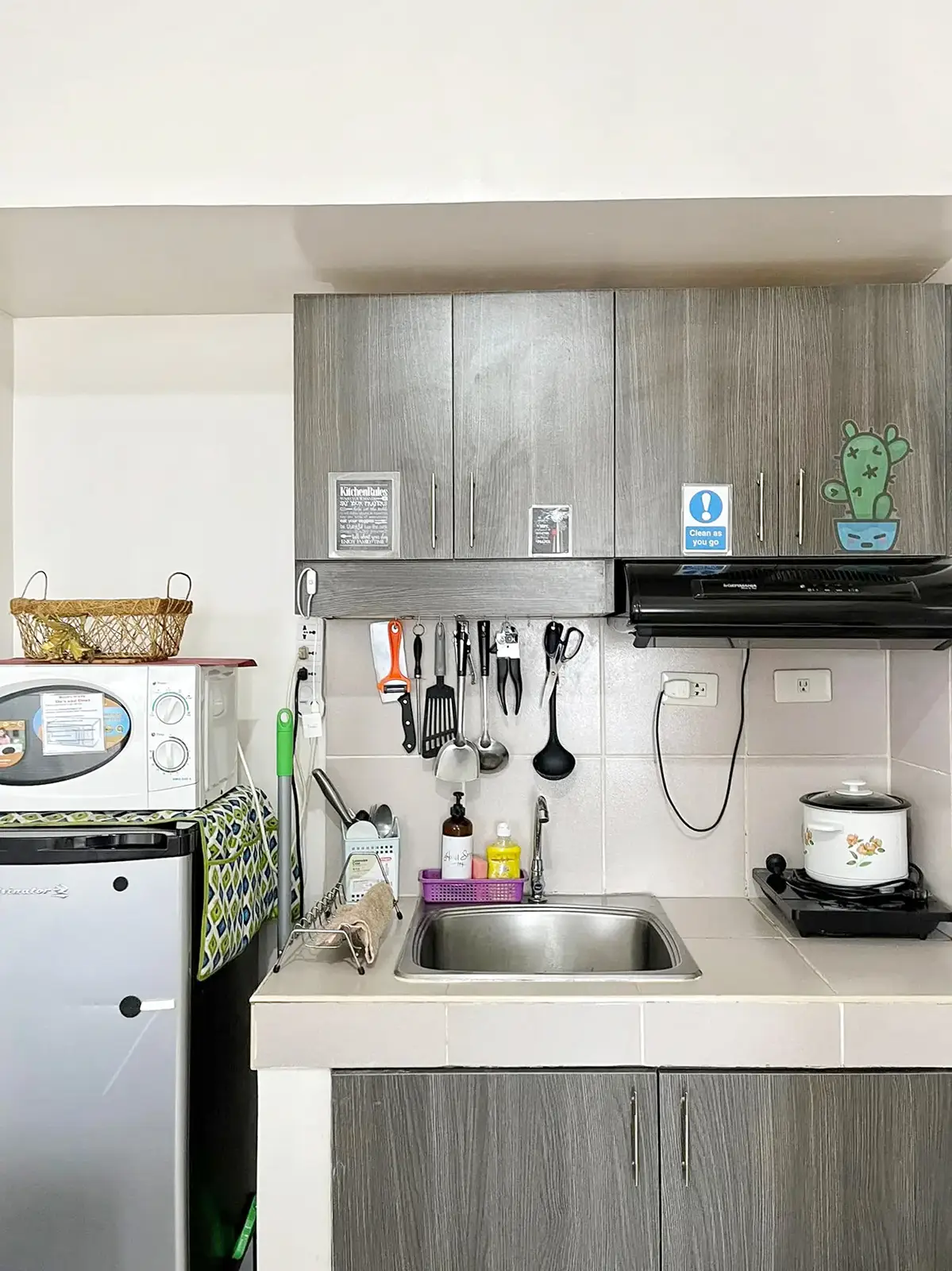 Compact kitchen with refrigerator, microwave, sink, rice cooker, and induction cooker