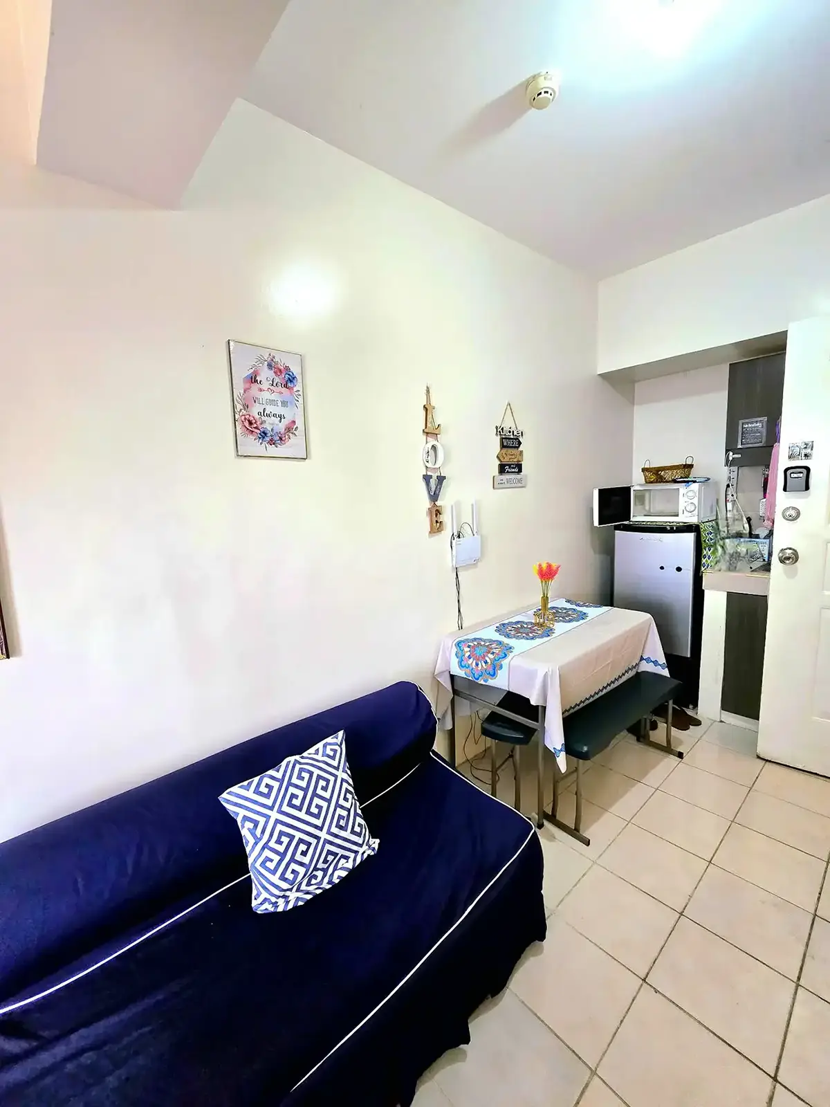 Living and dining area with a navy sofa, dining table, and compact kitchen